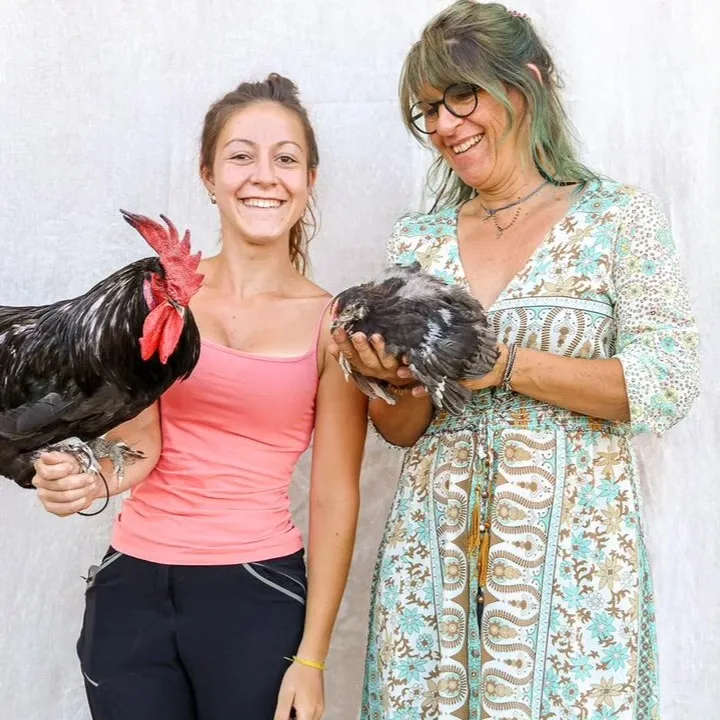 Gaëlle et sa fille devant la ferme, un coq et une poule dans les bras